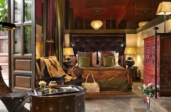 Luxurious Moroccan hotel room with arched doorway leading to private terrace, featuring traditional decor and ornate tile patterns