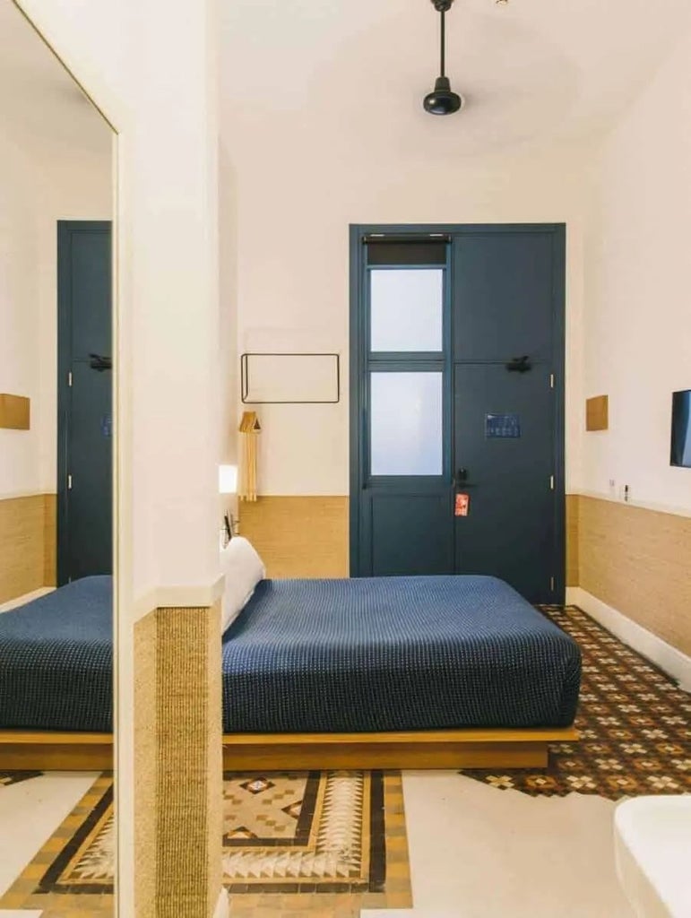 Minimalist hotel room with soft neutral tones, elegant wooden furniture, clean lines, and large windows offering natural light in Spanish boutique hotel