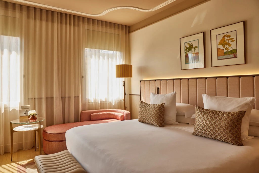 Luxurious deluxe hotel room in Spain with modern design, plush king bed, elegant wooden furnishings, and expansive city skyline view through large windows