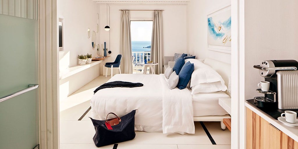 Luxurious white minimalist hotel room with panoramic sea view, crisp linens, modern design, and elegant Cycladic architecture in Mykonos, Greece