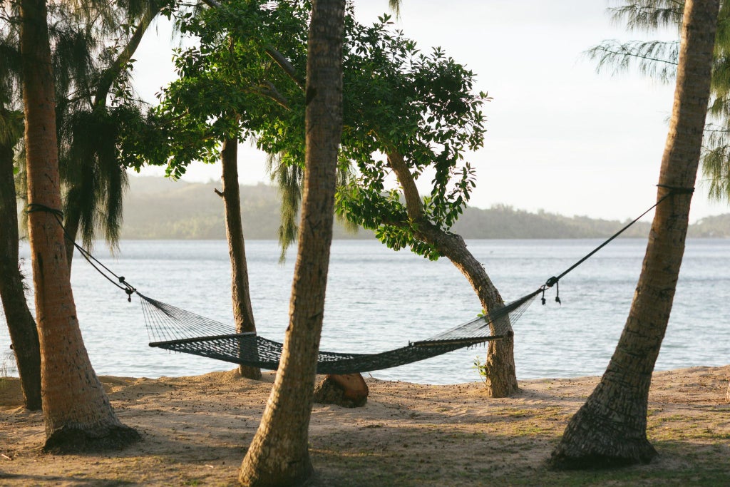 Spacious beachfront villa with panoramic ocean views, elegant wooden decor, king-sized bed, and direct access to pristine white sandy beach in tropical Fiji