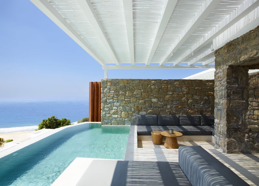 Luxurious modern villa overlooking the Aegean Sea, featuring an infinity pool, white curved architecture, and private terrace at sunset