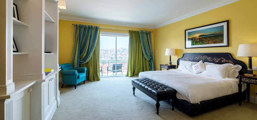 Elegant hotel room with plush king bed, floor-to-ceiling windows overlooking Porto's skyline, and contemporary white furnishings