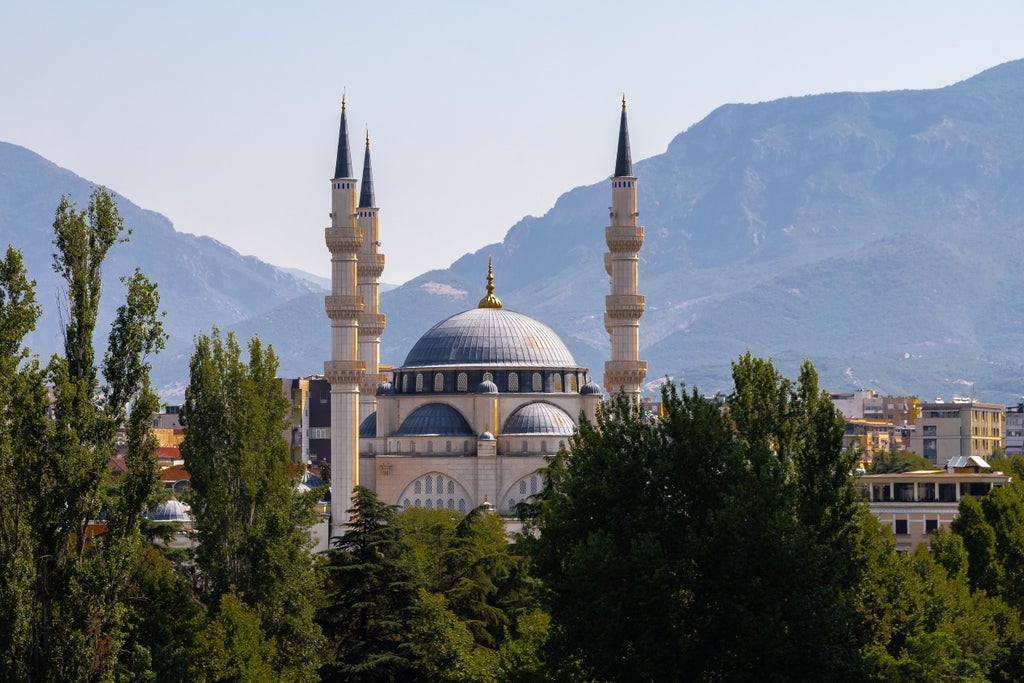 Elegant pedestrian strolling through vibrant Skanderbeg Square, surrounded by historic Ottoman and Italian architecture in downtown Tirana, Albania