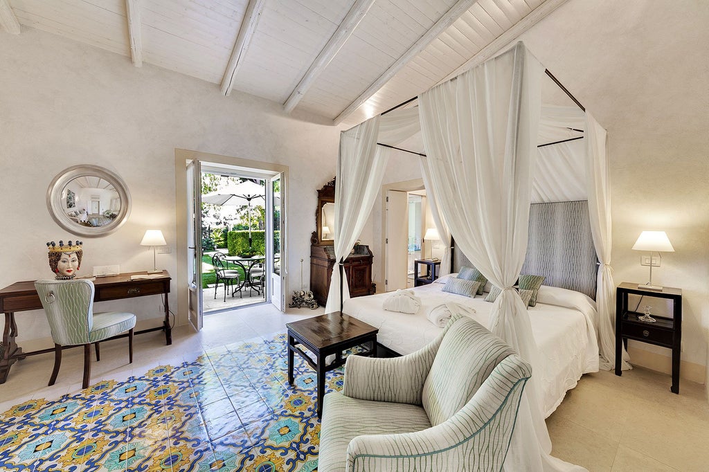 Elegant Italian luxury bedroom with soft white linens, antique wooden furniture, and delicate floral curtains in a sunlit Sicilian boutique hotel room