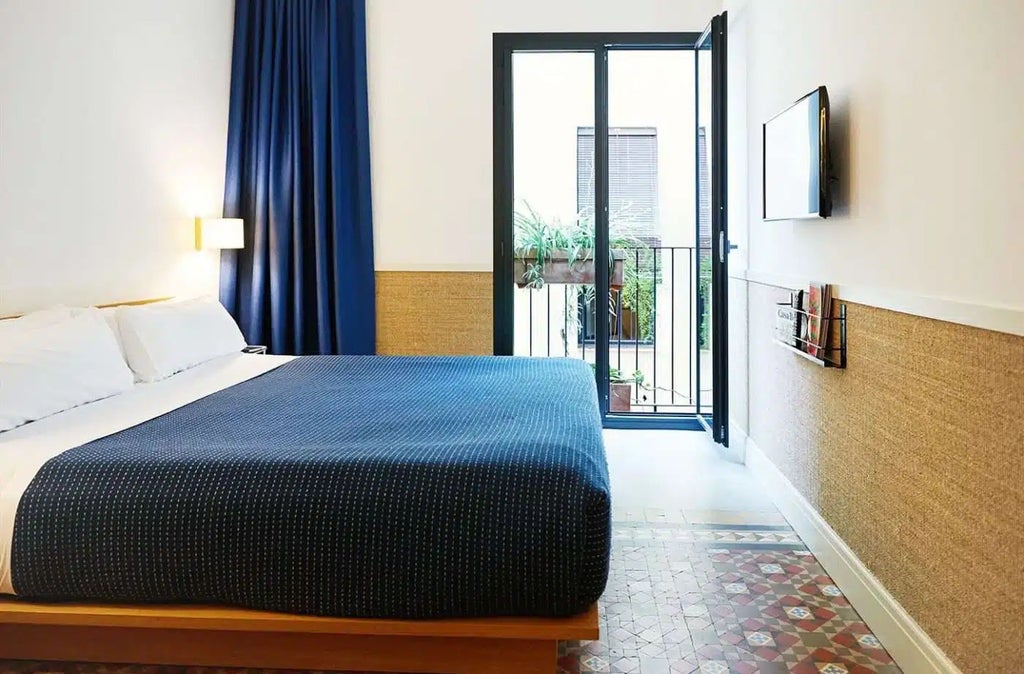 Sunlit Barcelona hotel room with minimalist design, featuring crisp white linens, wooden furniture, large windows, and a stylish urban aesthetic capturing Mediterranean elegance