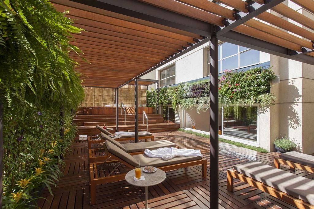 Contemporary white hotel facade with elegant vertical louvers, featuring geometric patterns and a luxurious entrance with tropical landscaping