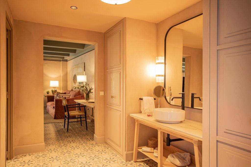 Elegant junior suite with whitewashed walls, traditional Spanish decor, ornate wooden furniture, and soft natural light in a historic Seville hotel.