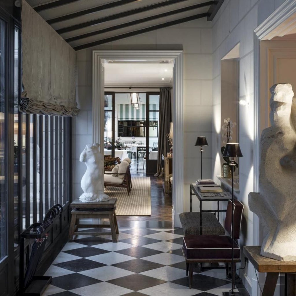 Elegant Parisian boutique hotel lobby with sophisticated white marble fireplace, plush velvet chairs, and chic contemporary design aesthetic