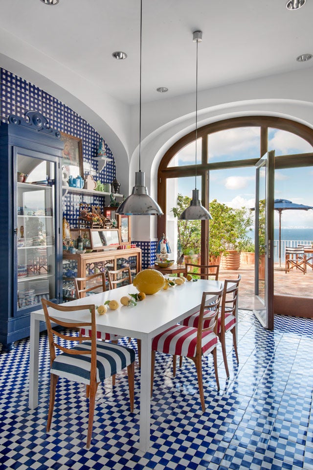 Elegant Mediterranean hotel with ocean-view terrace, white walls and blue accents, overlooking Bay of Naples and Mount Vesuvius