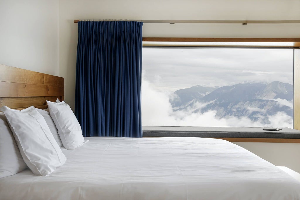 Luxurious alpine hotel room at Chetzeron with panoramic mountain views, modern minimalist design, and warm wooden accents in Swiss mountain landscape