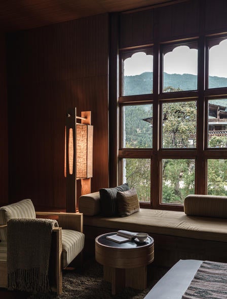 Luxurious mountain lodge with rustic stone walls and wood accents nestled in pine forest valley, featuring traditional Bhutanese architecture