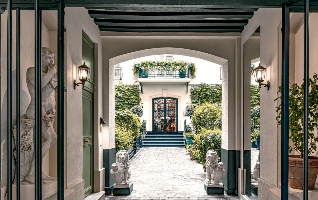 Elegant stone façade of boutique Parisian hotel Relais Christine with climbing ivy, arched windows and classic wrought-iron balconies