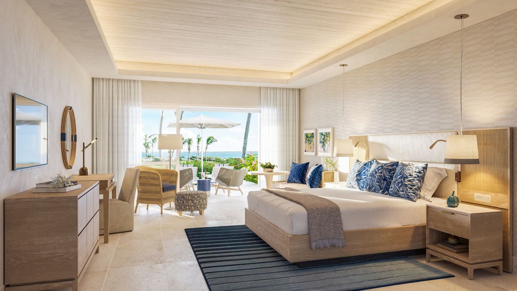 Luxurious junior suite with king bed, white linens, ocean-view terrace, and elegant Caribbean-inspired decor overlooking turquoise waters of Antigua