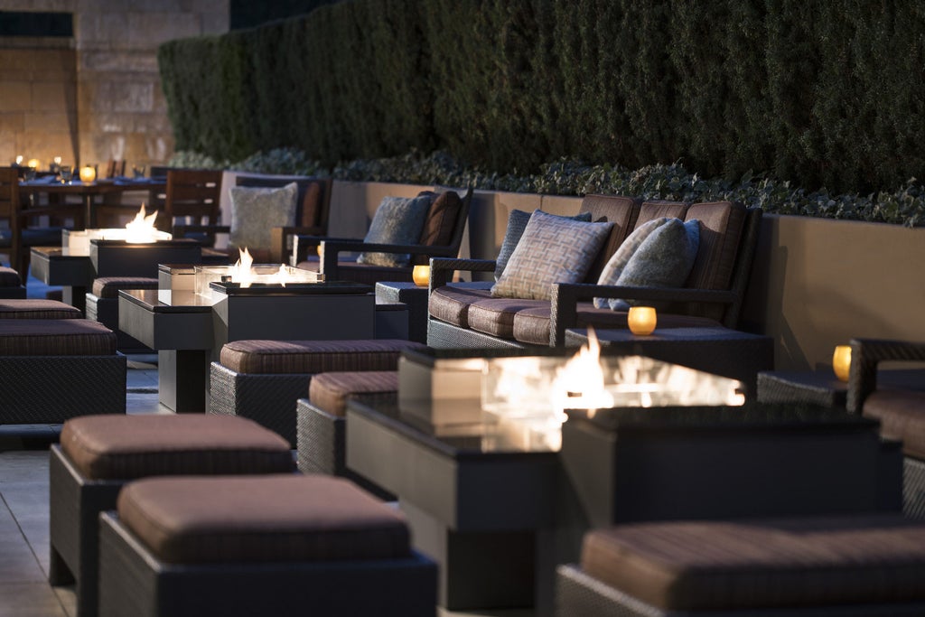 Elegant modern hotel exterior with glass facade, palm trees, and manicured gardens at Four Seasons Silicon Valley hotel entrance