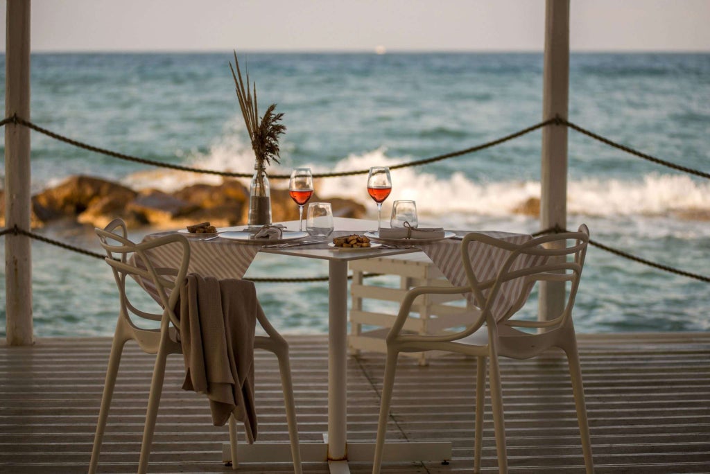 Luxurious coastal boutique hotel overlooking azure Adriatic waters, with elegant infinity pool blending seamlessly into scenic Italian landscape