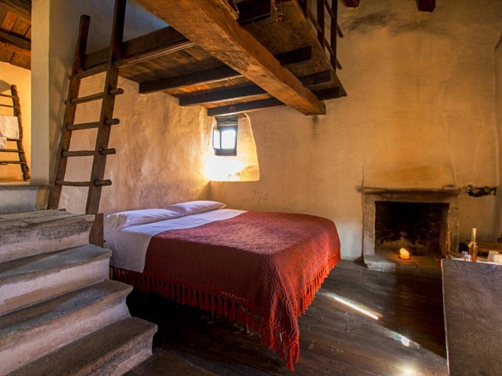 Rustic stone hotel nestled in an ancient Italian hillside village, showcasing traditional architecture with warm terracotta roofs and weathered stone walls at sunset