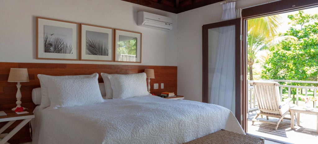 Elegant luxury suite with rustic Brazilian charm, featuring wooden furnishings, soft neutral tones, and expansive windows overlooking lush tropical landscape