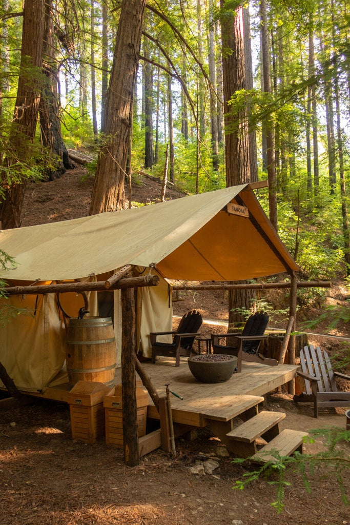 Luxurious safari-style tent nestled in California redwoods, featuring a private deck, plush king bed and upscale outdoor furnishings