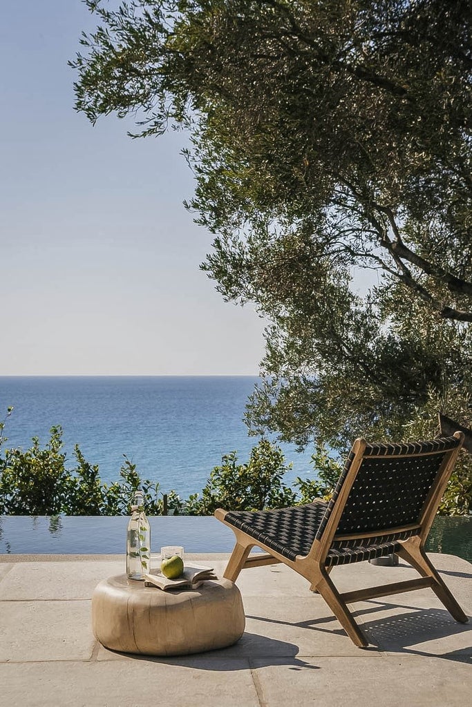 Luxurious Greek seaside resort with white minimalist architecture, infinity pool overlooking azure Kefalonian waters and lush Mediterranean landscape