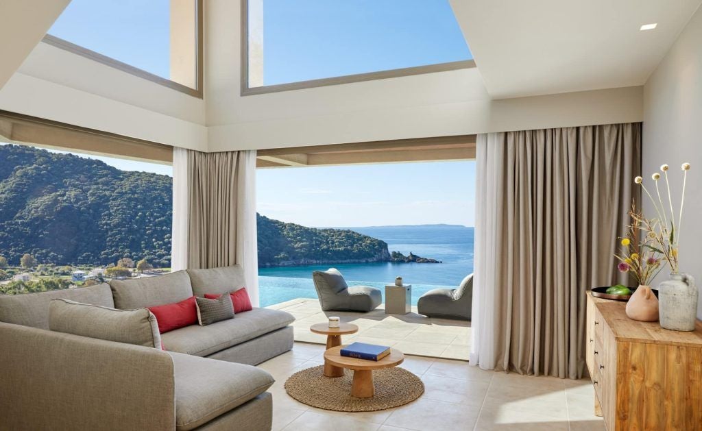 Luxurious two-story maisonette suite with private infinity pool overlooking azure waters, featuring modern minimalist design and elegant coastal Greece aesthetic