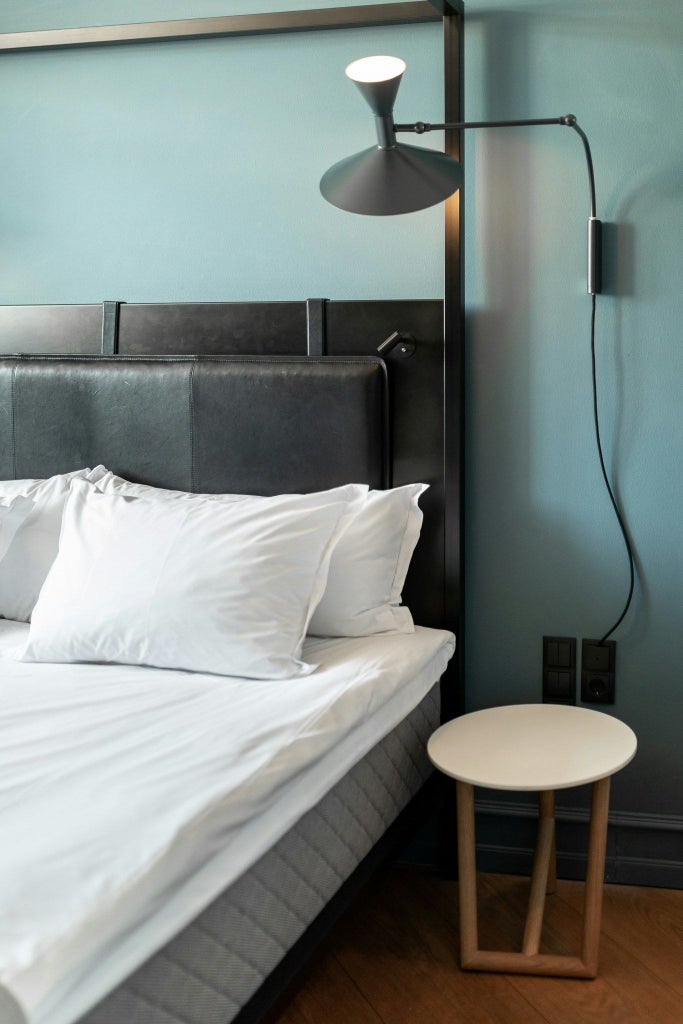 Elegant Danish design loft room with minimalist furnishings, warm wood tones, large windows, and contemporary urban luxury in Nobis Hotel Copenhagen