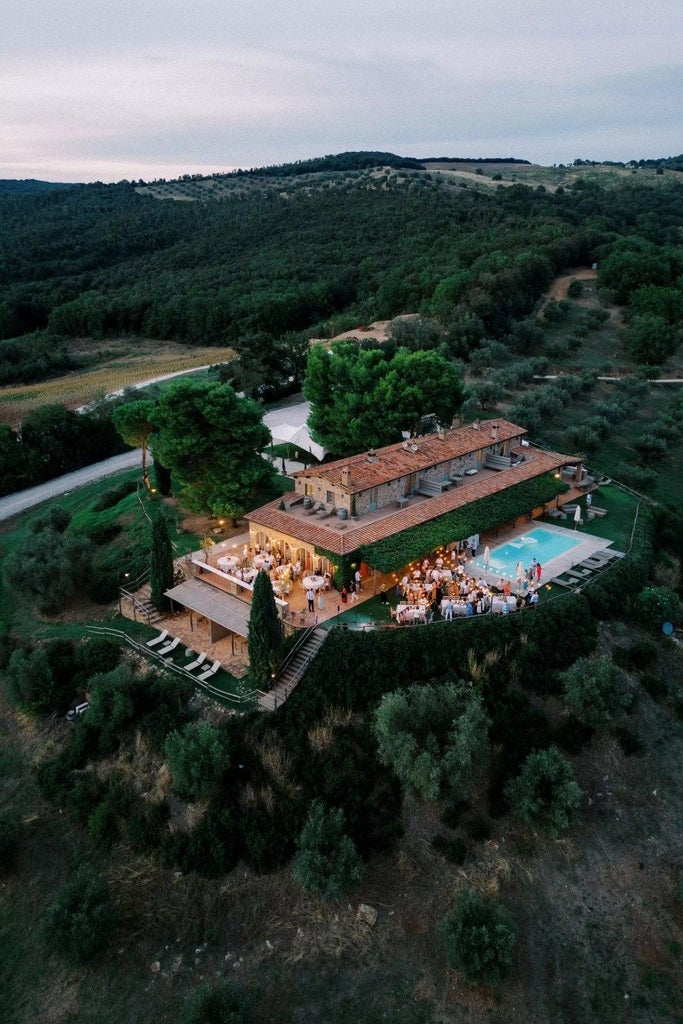 Elegant Tuscan wine estate with rolling vineyards, luxurious stone villa, golden sunset light casting warm glow on historic property landscape