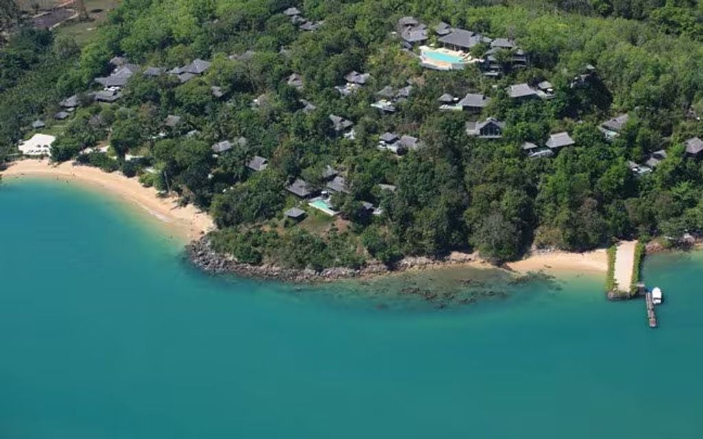 Luxury overwater villa with infinity pool overlooking limestone cliffs and turquoise waters of Thailand's Phang Nga Bay at sunset