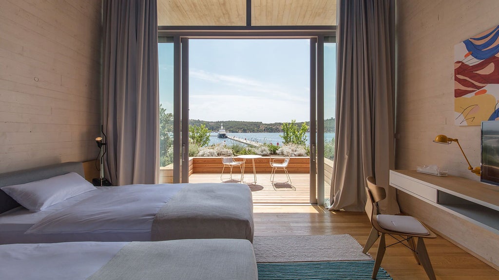 Spacious deluxe hotel room with panoramic sea view, modern minimalist design, crisp white linens, and elegant wooden furnishings overlooking Croatian coastline