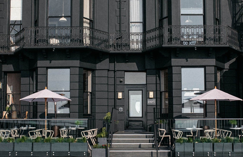 Elegant seaside Port Hotel with modern glass facade, wooden deck, and panoramic ocean view at sunset in coastal United Kingdom setting