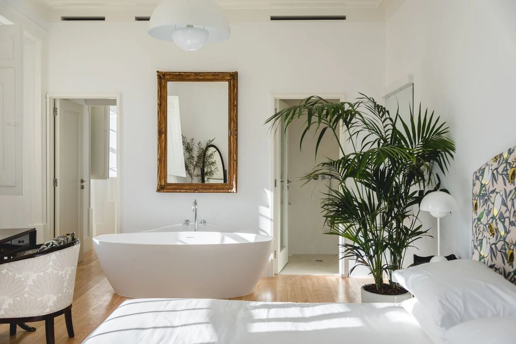 Bright, minimalist hotel suite with whitewashed walls, king bed, woven pendant lamp, natural wood accents and terrace overlooking Lagos cityscape