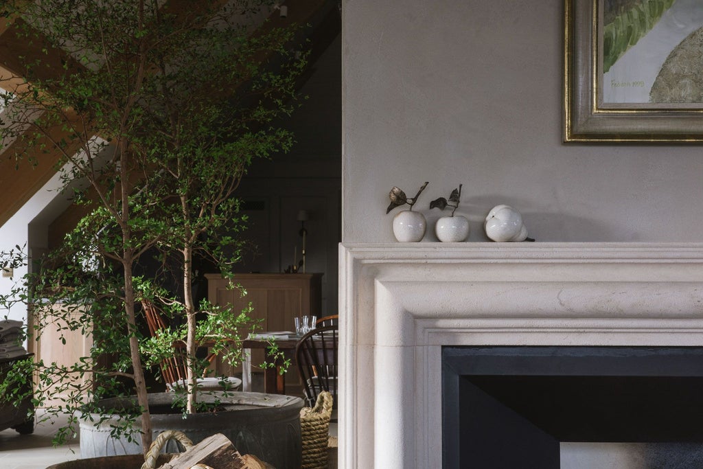 Elegant long room at luxury countryside estate with soft neutral tones, antique furniture, and expansive natural light from tall windows overlooking verdant landscape