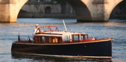 Elegant white cruise boat gliding on the Seine River at dusk, Eiffel Tower silhouetted against sunset, Parisian cityscape reflecting on calm waters