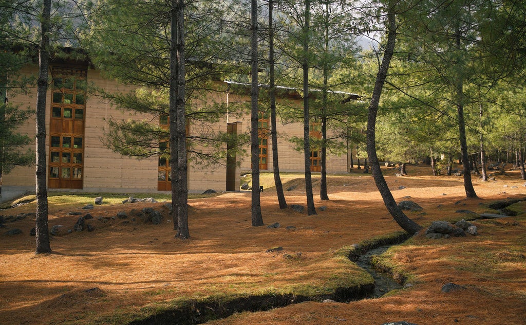 Luxurious mountain lodge with traditional Bhutanese architecture overlooking snow-capped Himalayan peaks and dense pine forest