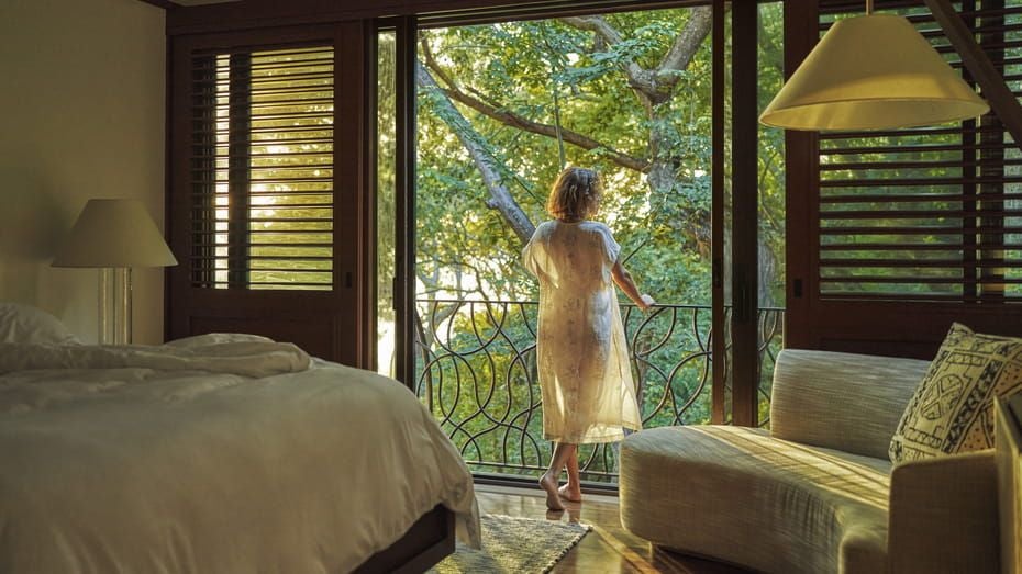 Luxurious one-bedroom suite with canopy bed, private balcony overlooking Costa Rican jungle, and modern tropical-inspired decor