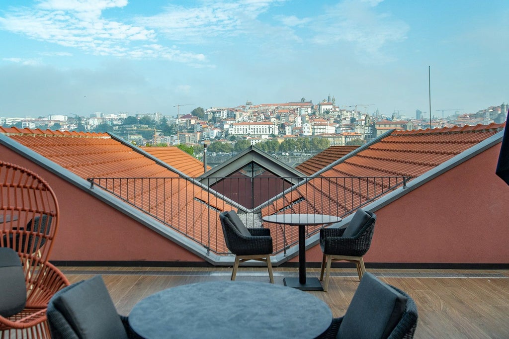 Elegant five-star Porto hotel featuring modern gray facade, floor-to-ceiling windows, and manicured landscaping along cobblestone street