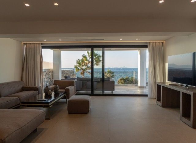 Luxurious master suite with panoramic Aegean Sea view, featuring elegant white decor, private jacuzzi, and contemporary minimalist design in Greek coastal hotel