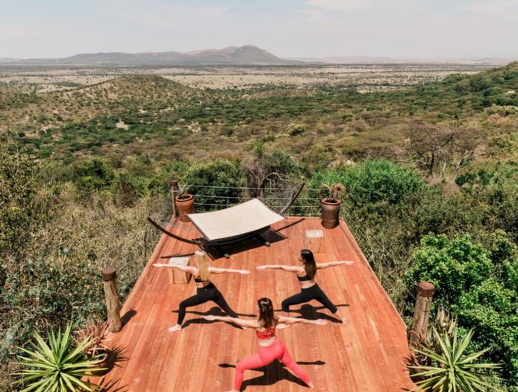 Elegant safari tent at Cottar's Camp overlooks vast Kenyan savanna, furnished with vintage decor and private veranda at sunset