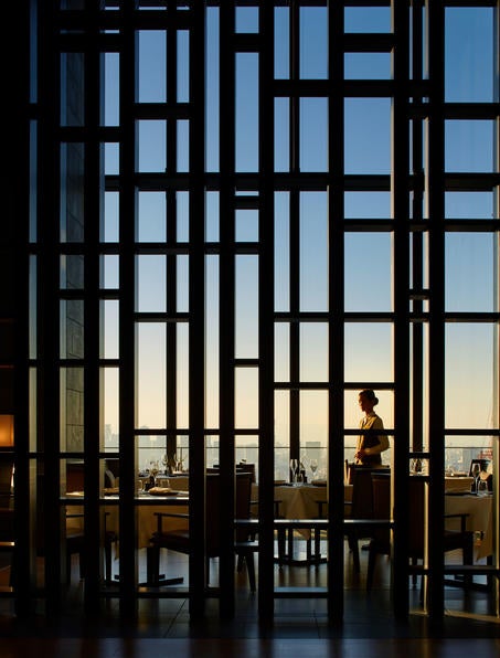 Elegant minimalist lobby of Aman Tokyo featuring soaring stone walls, traditional Japanese lanterns and floor-to-ceiling windows overlooking the city