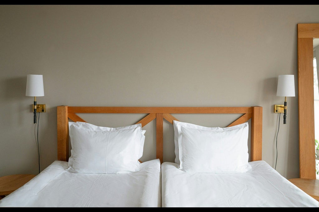 Spacious modern hotel room with panoramic floor-to-ceiling windows overlooking tranquil blue ocean waters and minimalist Scandinavian design elements