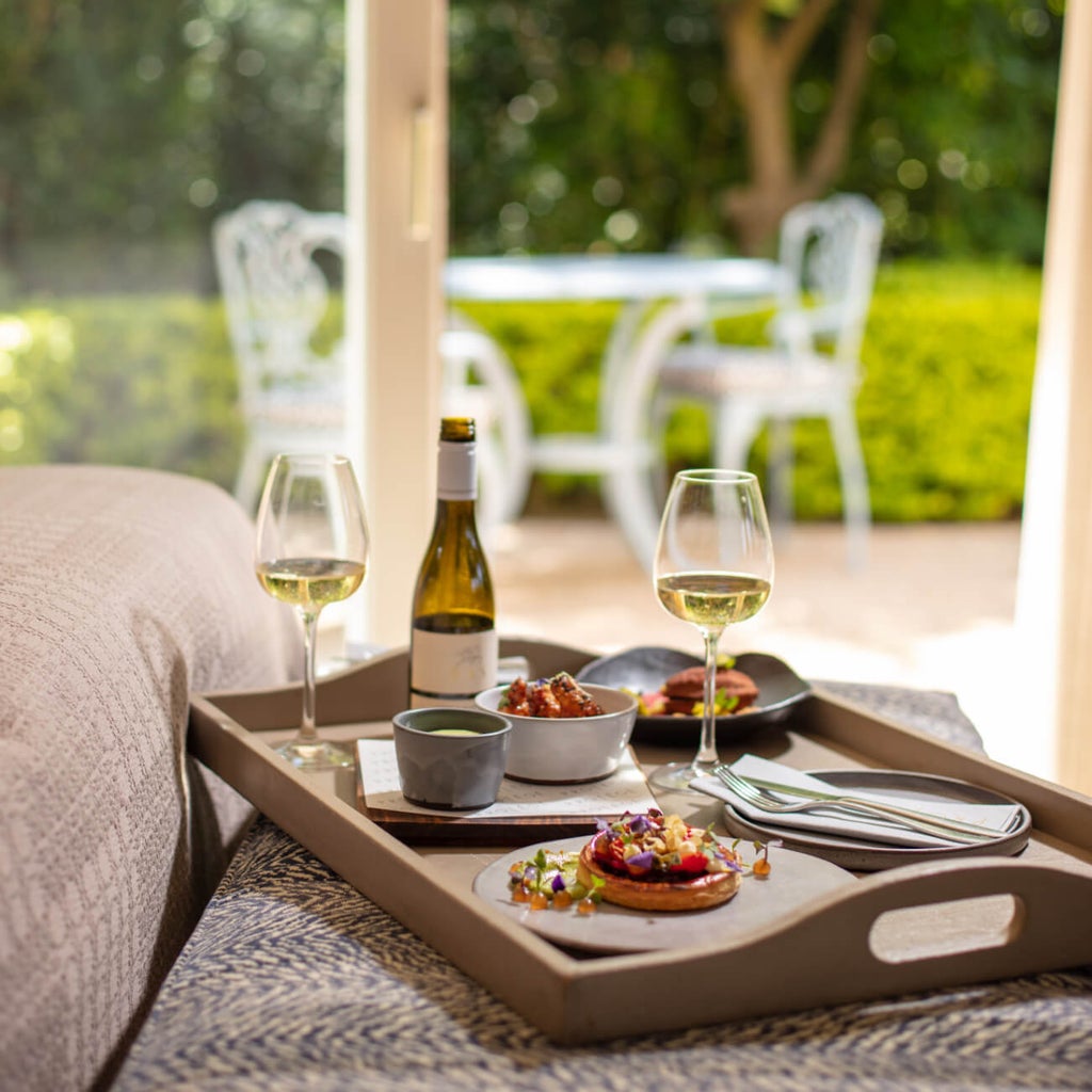 Elegant colonial-style hotel exterior with manicured gardens, white pillared facade, and French windows in Franschhoek wine country