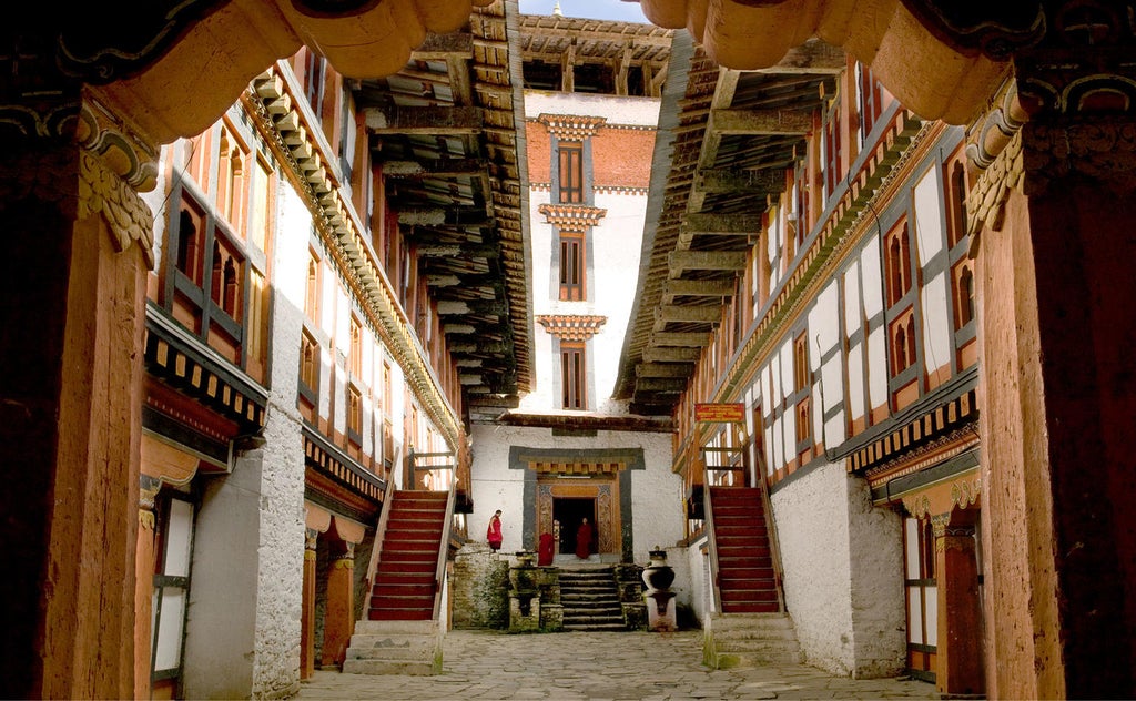 Serene Bhutanese luxury lodge nestled in pine forest, featuring traditional architecture with white walls and wooden accents at dusk