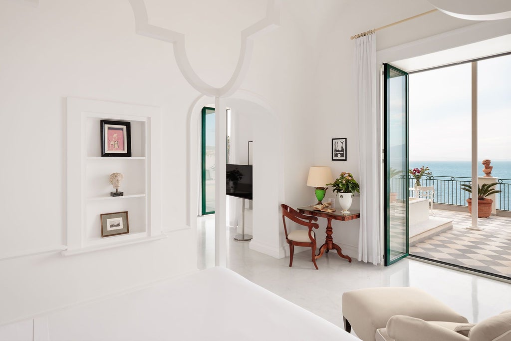 Elegant marble-floored suite with panoramic Neapolitan coastline view, ornate four-poster bed, and sweeping Vesuvius backdrop through expansive windows