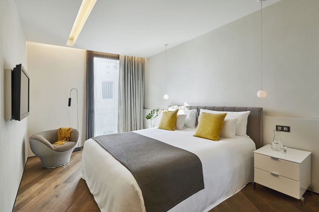 Sleek, modern hotel room with minimalist design, crisp white linens, elegant wood furnishings, and floor-to-ceiling window overlooking Barcelona's urban landscape