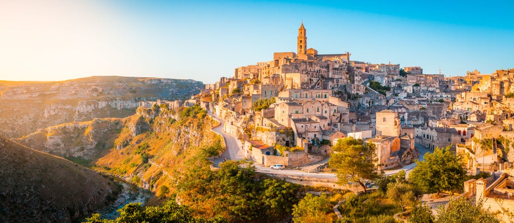 Tuscan countryside with medieval towers of San Gimignano rising above golden hills, vineyard terraces and cypress trees in warm sunlight