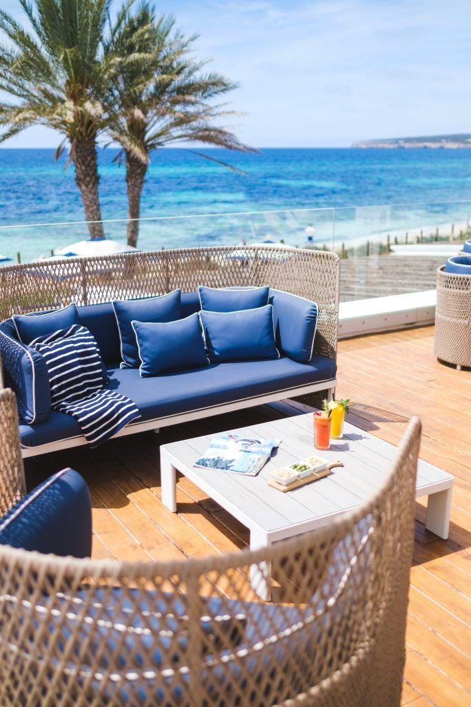 Luxurious beachfront loft with minimalist design, white decor, large windows overlooking turquoise Mediterranean waters at Gecko Hotel & Beach Club, Spain