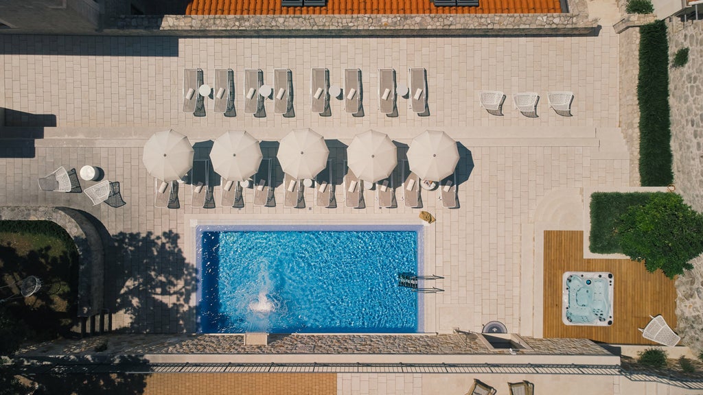 Croatian seaside luxury hotel with white stone facade, ornate balconies, and palm trees against blue Adriatic waters at sunset