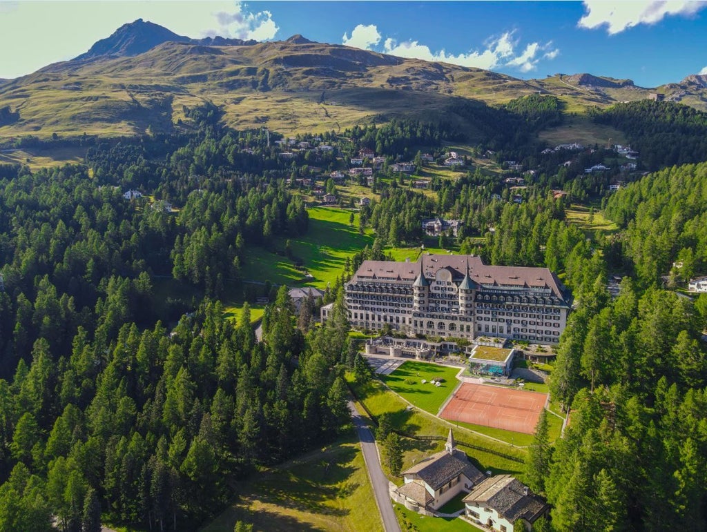 Elegant alpine resort hotel with grand stone facade nestled in snowy Swiss mountains, featuring classic Belle Époque architecture