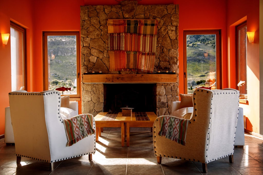 Modern mountain lodge with stone facade and glass windows overlooking snow-capped Andes peaks in El Chalten at golden hour