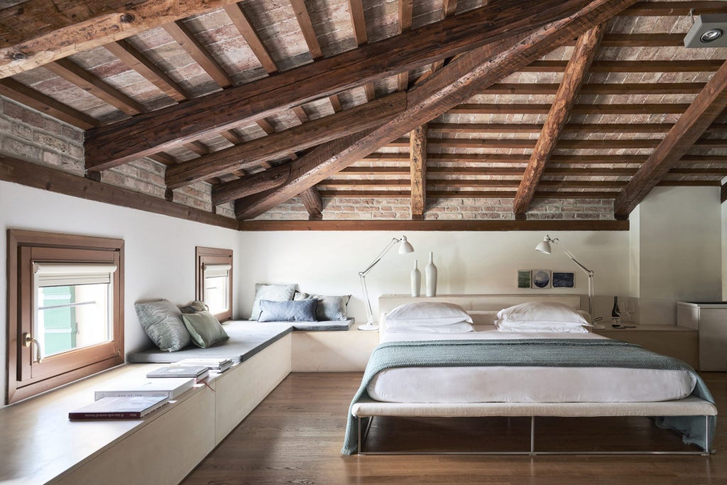 Elegant hotel room with exposed wood beams, white walls, designer furniture, and large windows overlooking Italian vineyard views